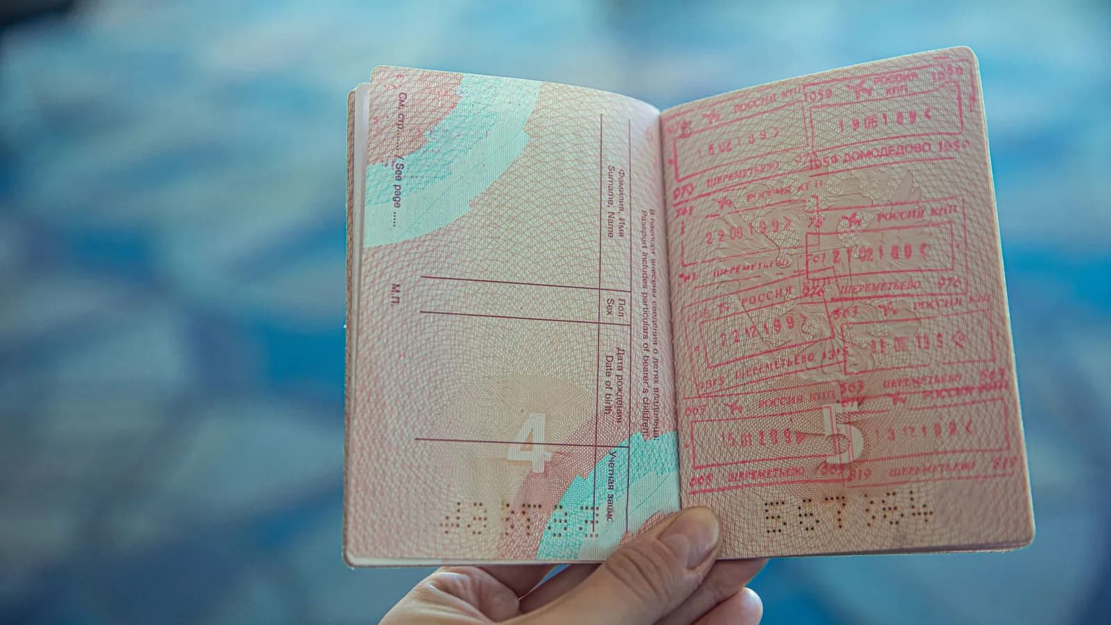 Passeport ouvert tenu à la main, page couverte de tampons de contrôle aux frontières