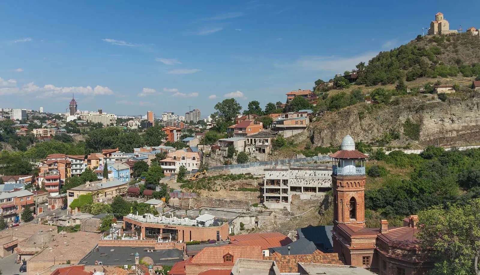Toits de la vieille ville de Tbilissi vus depuis la forteresse de Narikala, avec un minaret en brique et une colline couronnée d'une église