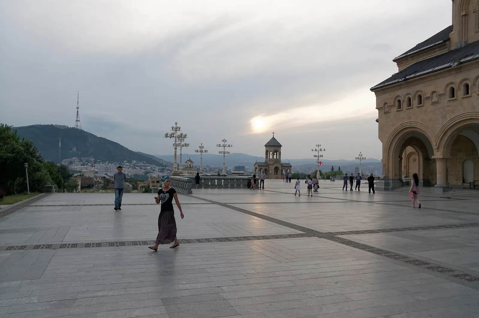 Parvis de la cathédrale de la Sainte-Trinité (Sameba) à Tbilissi au crépuscule, avec la ville, la colline de Mtatsminda et sa tour de télévision en arrière-plan