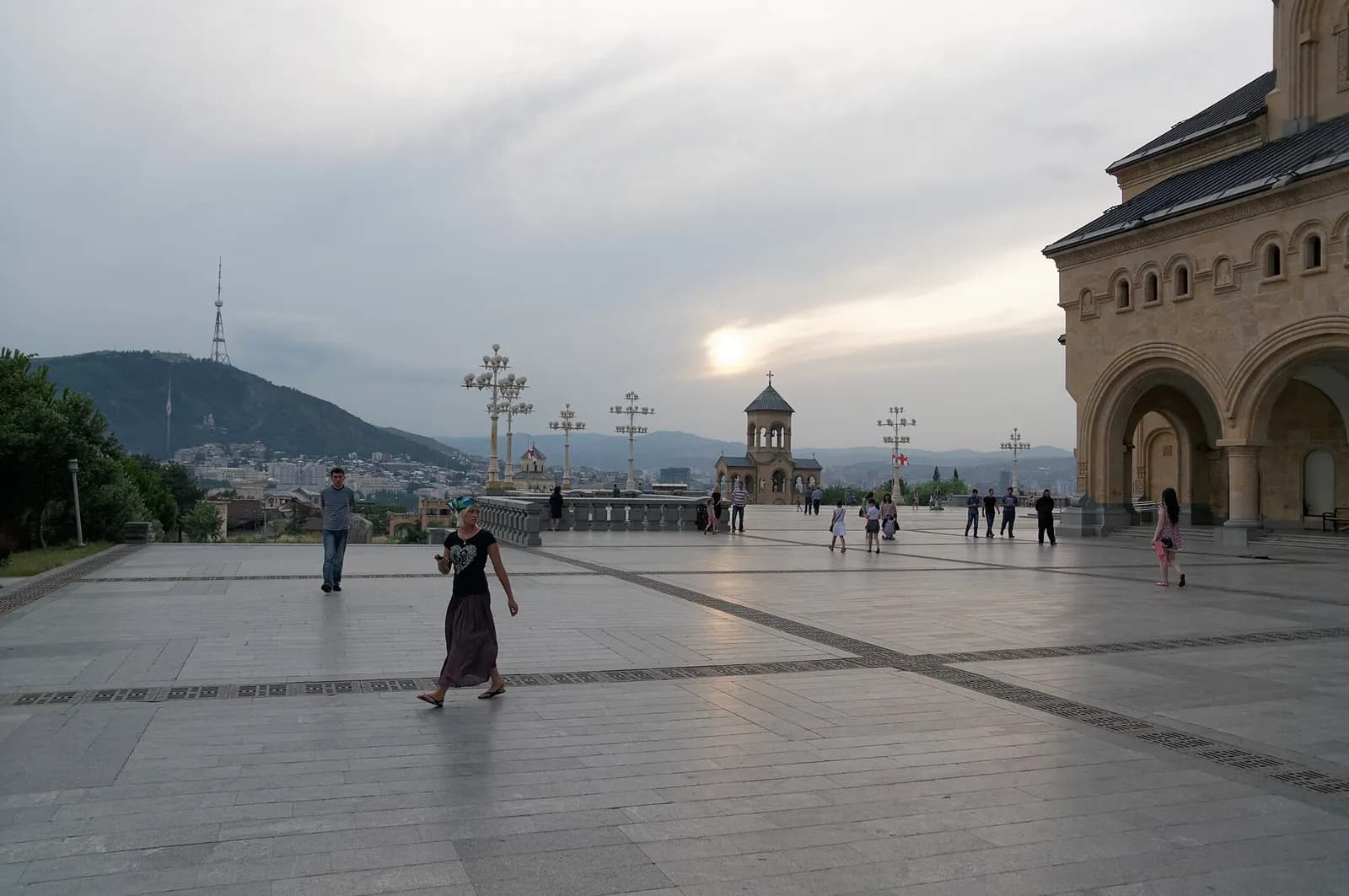 Parvis de la cathédrale de la Sainte-Trinité (Sameba) à Tbilissi au crépuscule, avec la ville, la colline de Mtatsminda et sa tour de télévision en arrière-plan