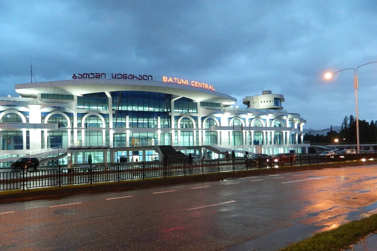 Façade éclairée de la gare centrale de Batoumi (Batumi Central) un soir de pluie