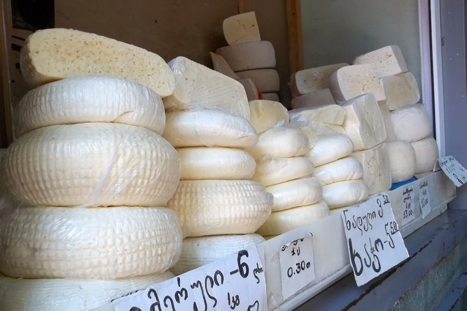 Meules et blocs de fromages géorgiens empilés sur l'étal d'une boutique de Tbilissi