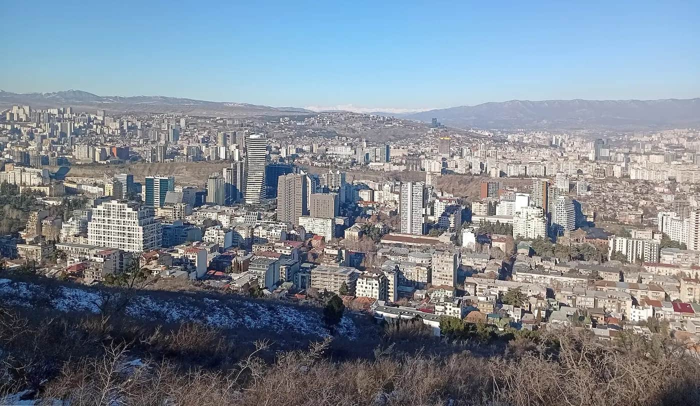 Panorama de Tbilissi depuis les hauteurs de Vake : tours et immeubles récents du centre moderne, avec les montagnes au fond