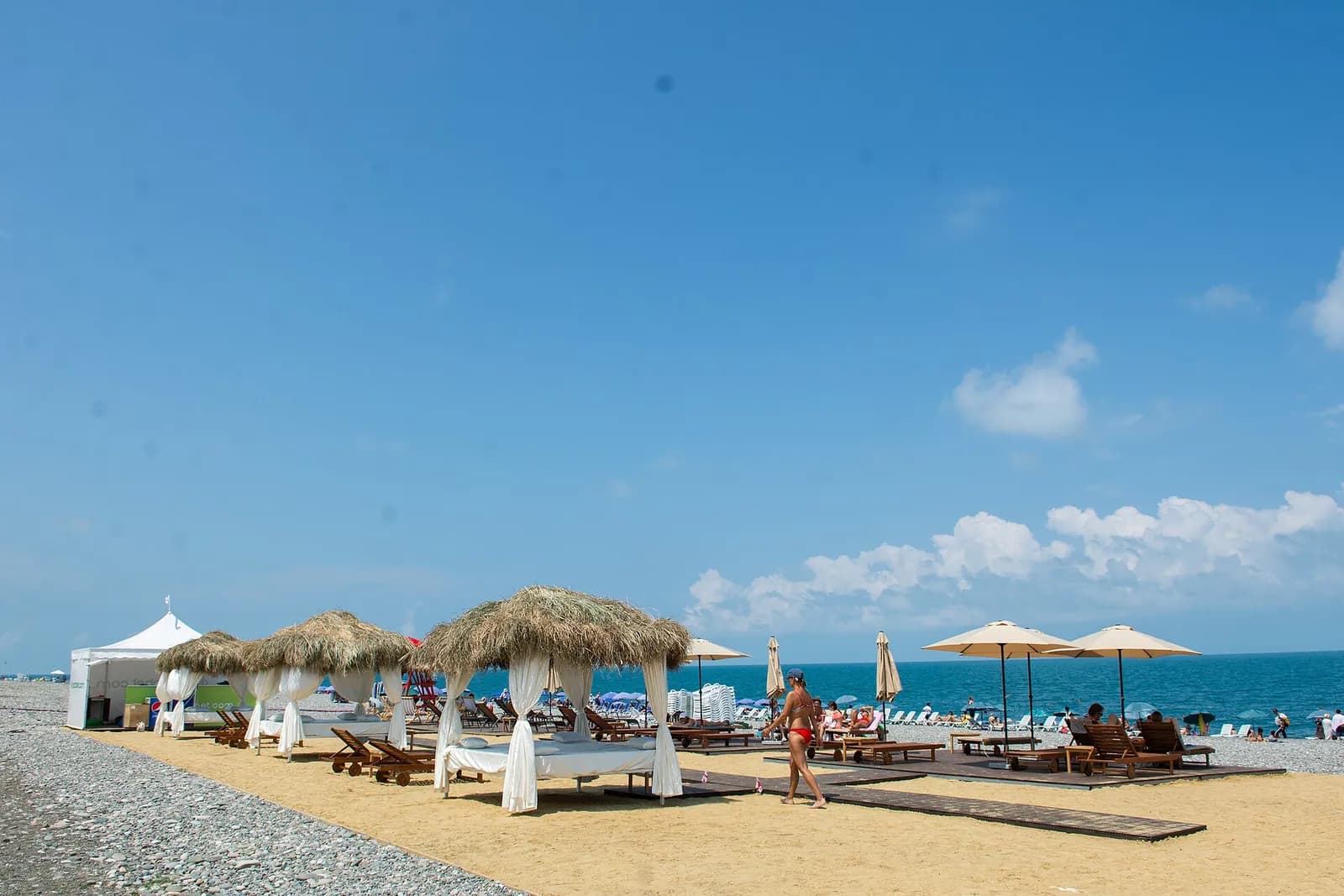 Cabanes de plage à toit de chaume et transats sur la plage du boulevard de Batoumi