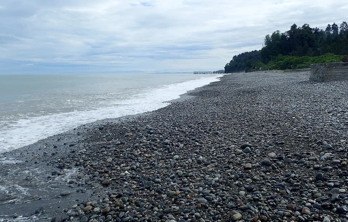 Plage de galets de Mtsvane Kontskhi (Cap Vert), près de Batoumi, avec la mer, les vagues et une jetée au loin