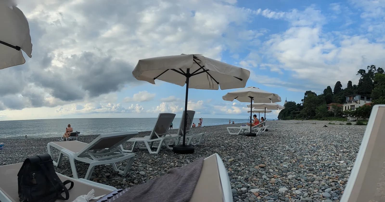 Plage de galets de Tsikhisdziri, avec transats, parasols et la côte boisée