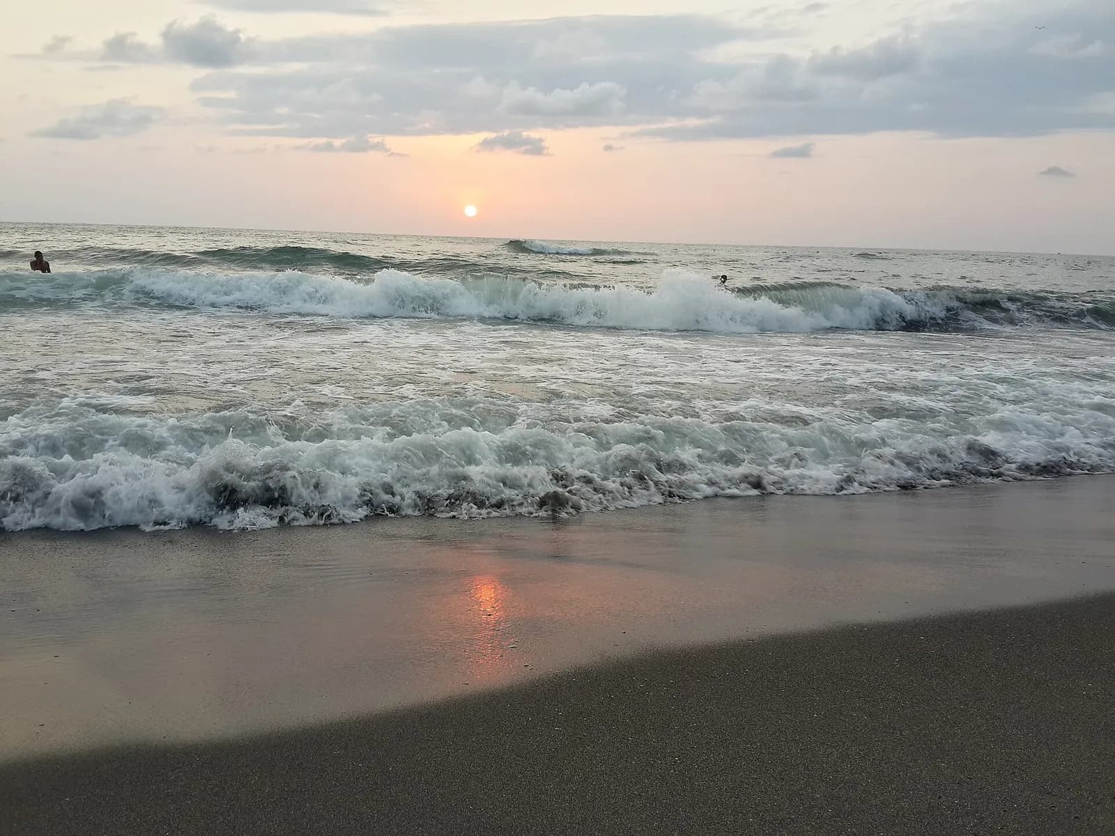 Vagues et sable sombre au coucher du soleil sur la côte d'Ureki, mer Noire