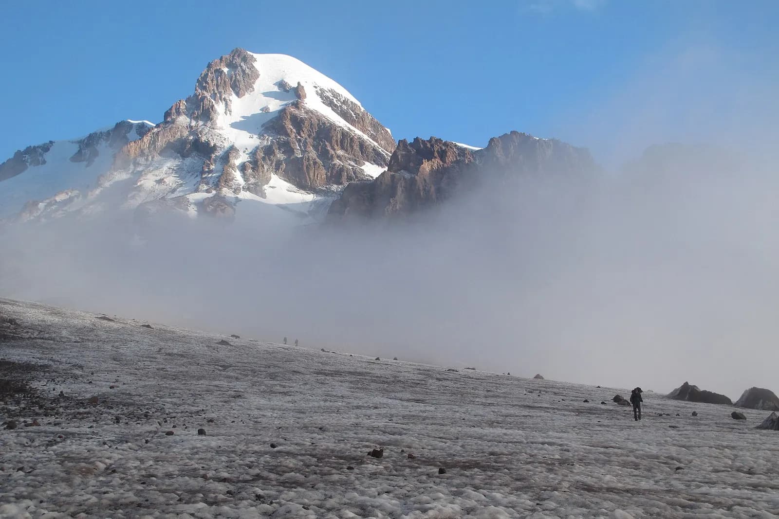 Le glacier de Gergeti sous le sommet du mont Kazbek, en Géorgie, avec des randonneurs au loin