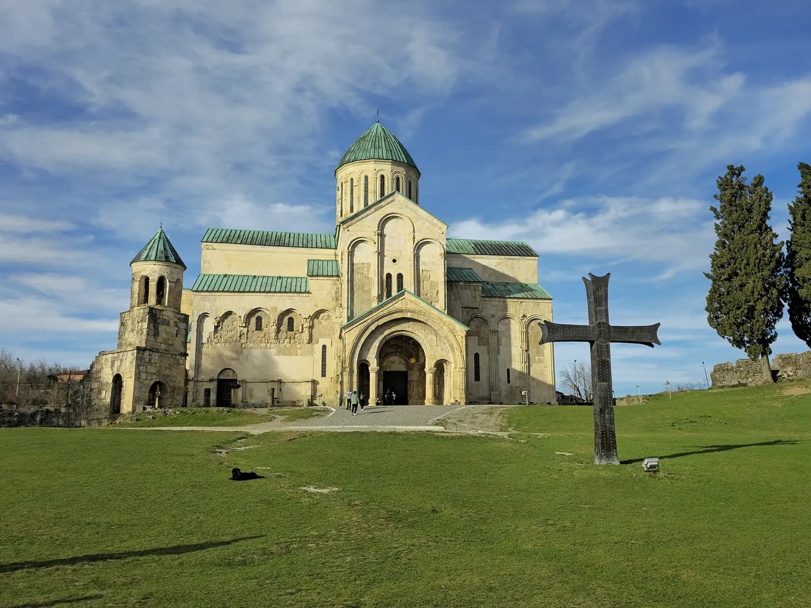 Façade de la cathédrale de Bagrati à Koutaïssi, toits en cuivre vert-de-gris, clocher et croix métallique sur la pelouse