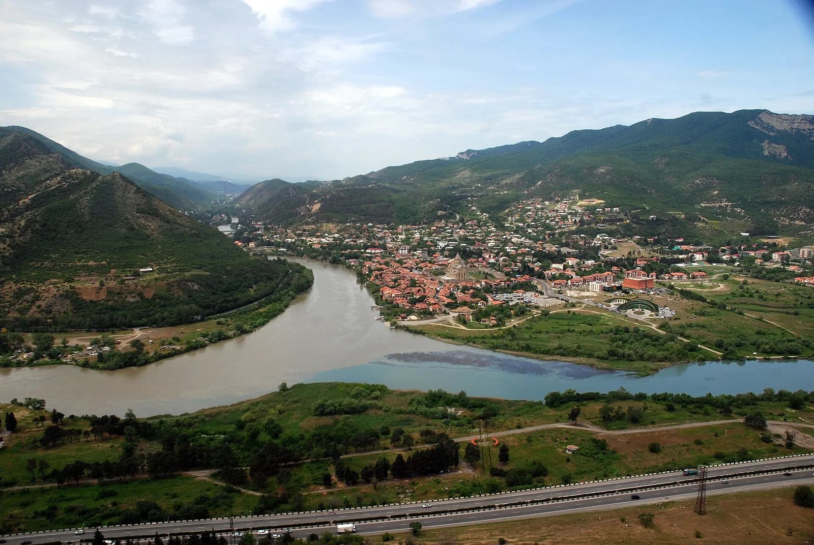 Vue depuis les hauteurs de Jvari sur la confluence de l'Aragvi (eau brune) et de la Koura (eau bleutée), avec la ville de Mtskheta et ses toits rouges
