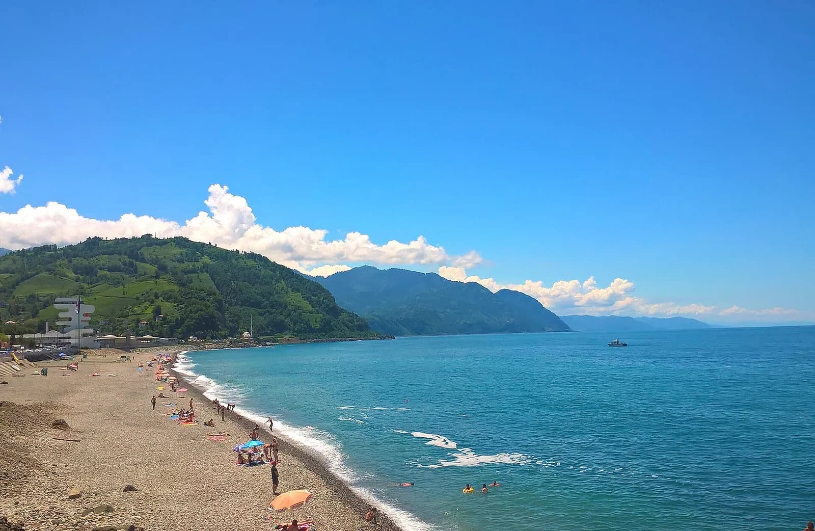 Plage de galets de Sarpi en été, baigneurs et parasols au bord de la mer Noire, près de la frontière turque
