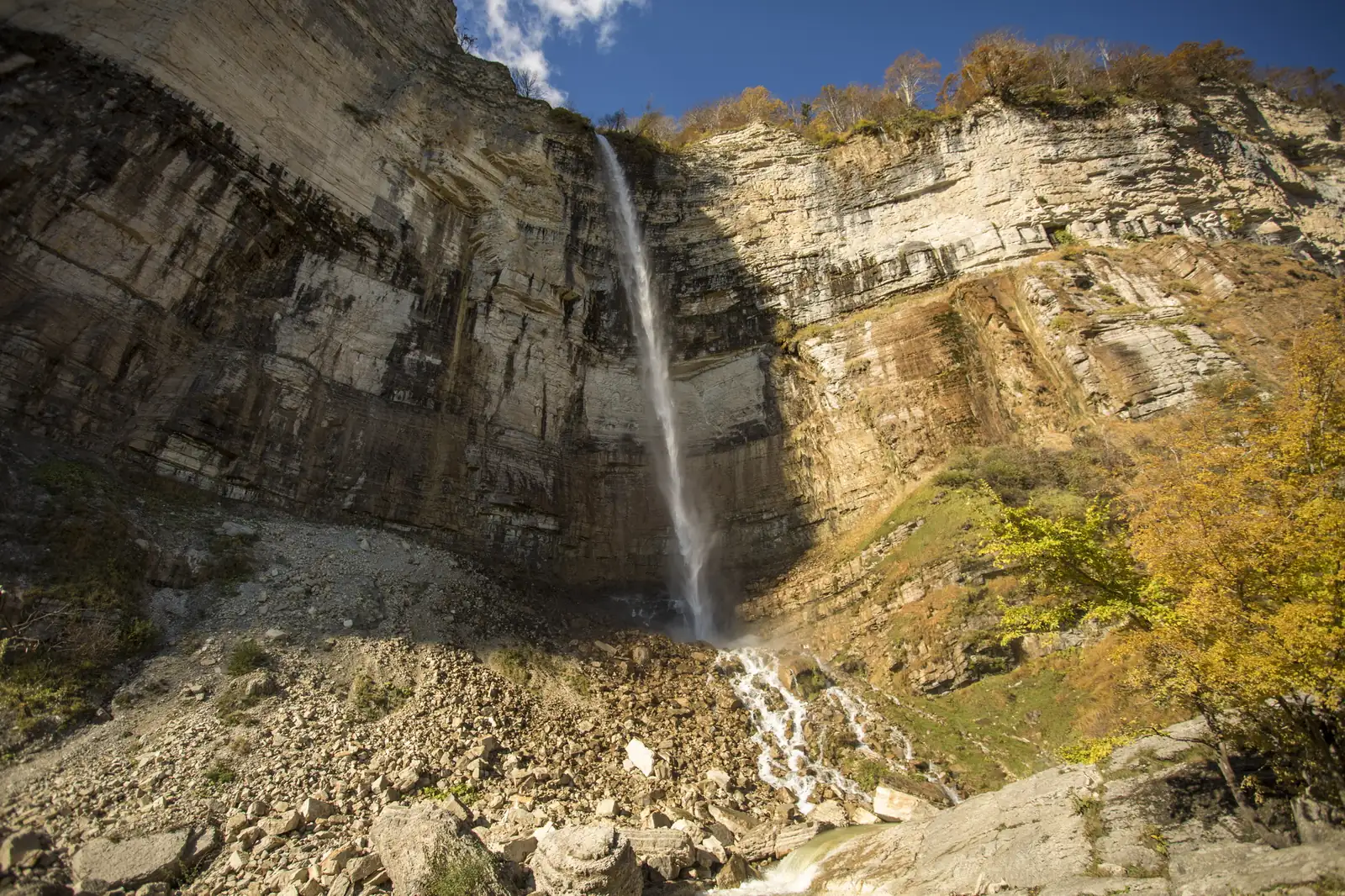 Cascade de Kinchkha, au bord du canyon d'Okatsé en Imérétie, tombant d'une haute falaise calcaire sous un ciel bleu d'automne