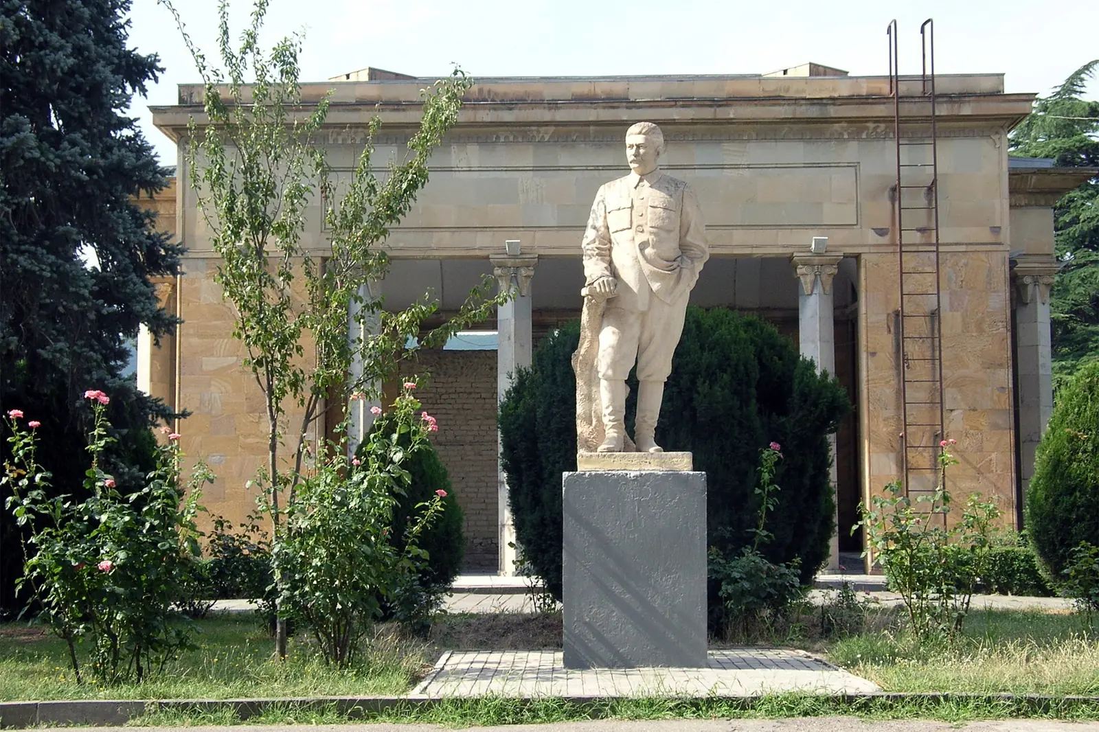 Statue blanche de Staline devant le pavillon en pierre qui abrite sa maison natale, dans le parc du musée Staline de Gori