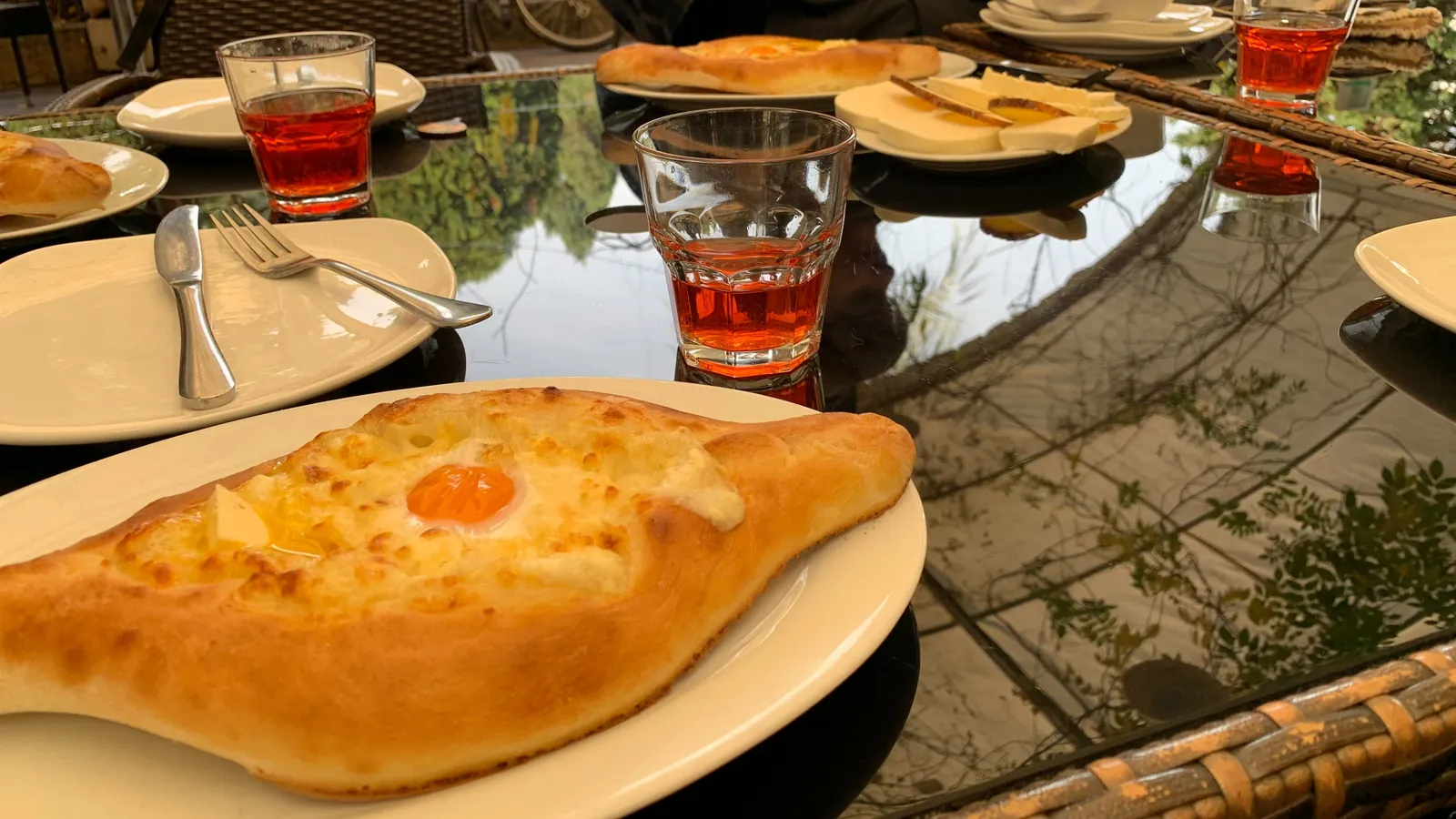 Khachapuri adjarien doré, garni de fromage fondu, de beurre et d'un jaune d'œuf, servi sur une table de restaurant à Batoumi