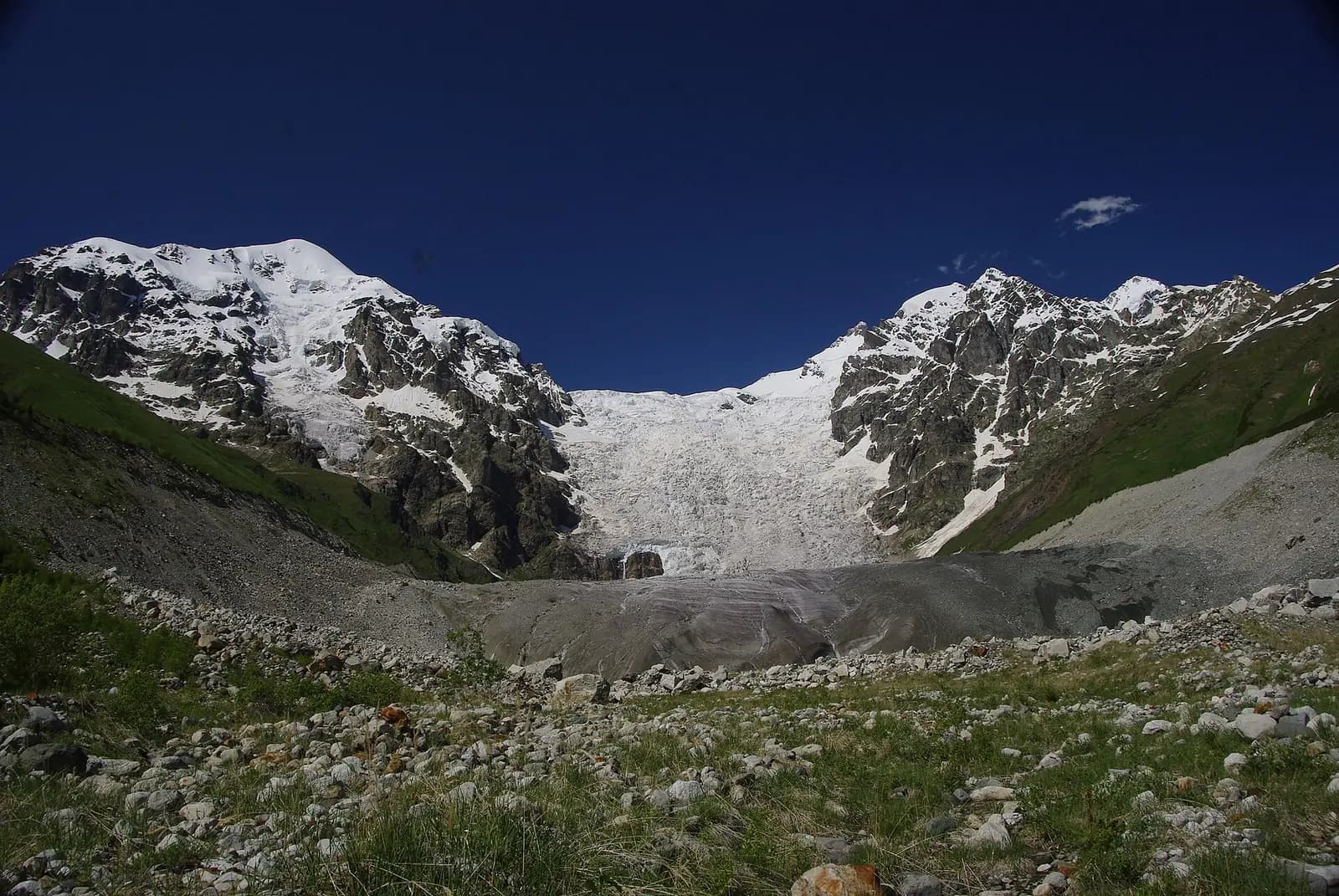 Glacier d'Adishi en Svanétie, cascade de glace entre deux sommets enneigés du Caucase, au-dessus d'une moraine et de pentes d'éboulis