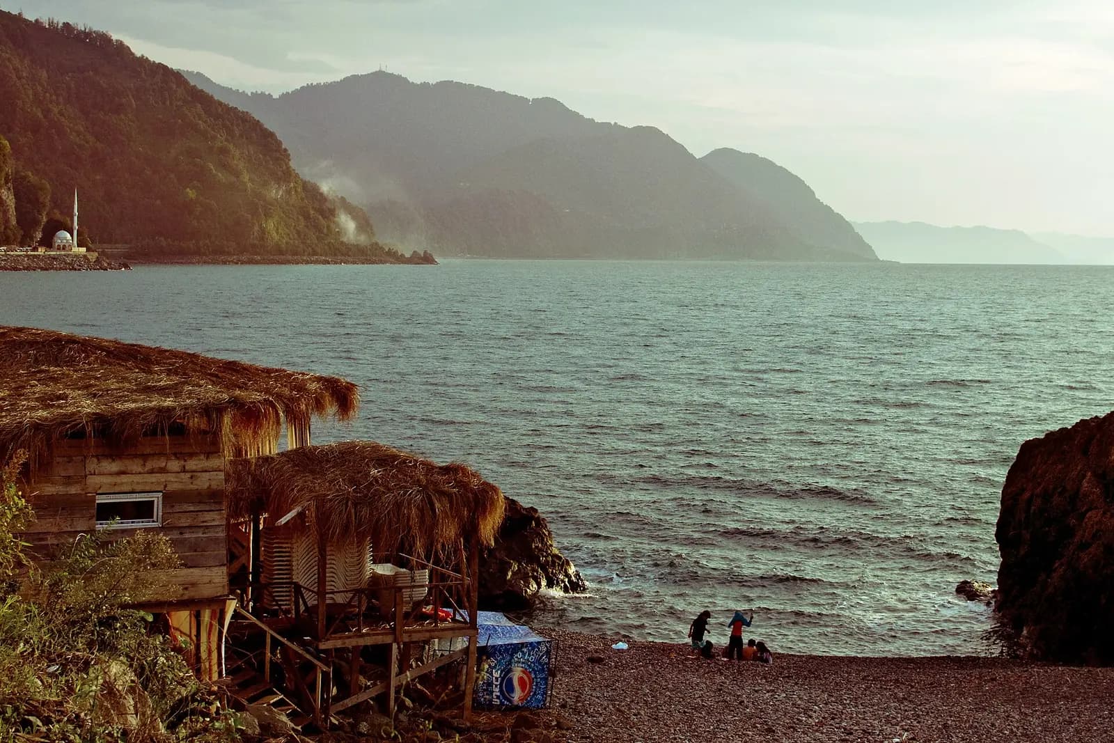 Côte rocheuse et petite plage de galets à Sarpi, cabane au toit de chaume face à la mer Noire