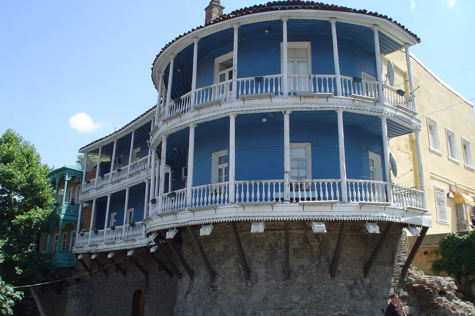 Maison aux balcons de bois bleus et blancs construite sur un pan de rempart dans la vieille ville de Tbilissi