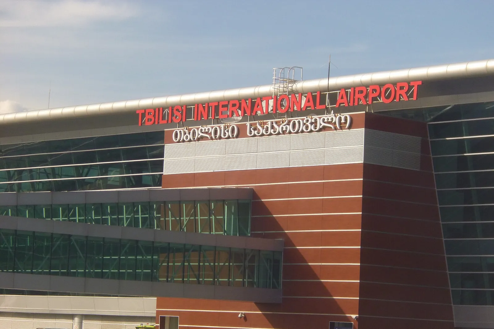 Façade du terminal de l'aéroport international de Tbilissi avec l'enseigne en anglais et en géorgien