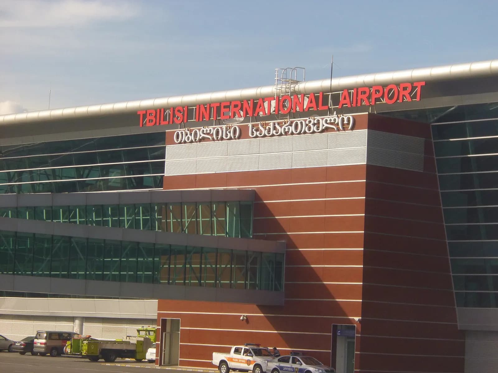 Façade du terminal de l'aéroport international de Tbilissi, enseigne en anglais et en géorgien